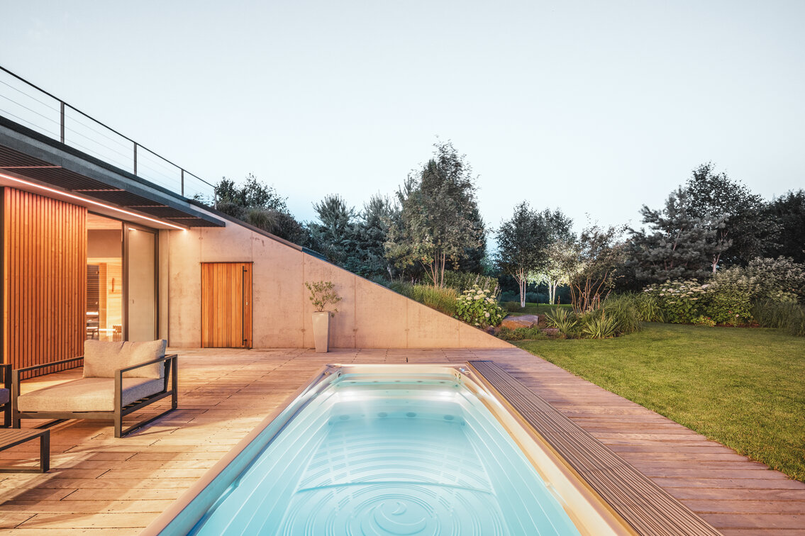 Swim Spa XL od USSPA integrovaná do dřevěné terasy, obklopená vzrostlou zahradou